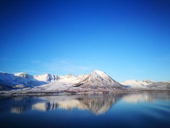 Scenic view of lake and snowcapped mountains against clear blue sky