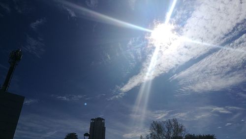 Low angle view of sun shining over buildings in city