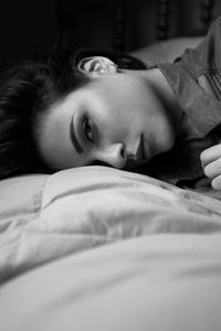 Portrait of young woman lying on bed at home