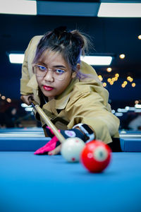 Portrait of young woman playing pool