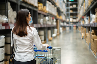 Rear view of woman wearing mask standing in warehouse