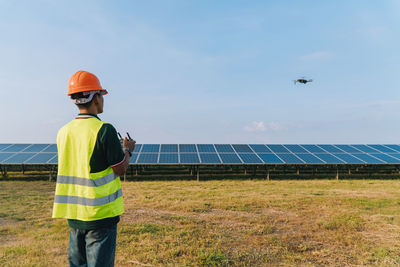 Man working with umbrella standing against sky