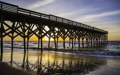 Silhouette pier over sea against sky during sunset