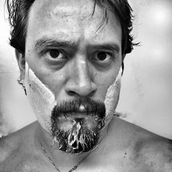 Close-up portrait of mid adult man shaving beard