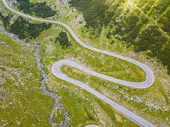 Winding road through the forest, from high mountain pass, in summer time. aerial view