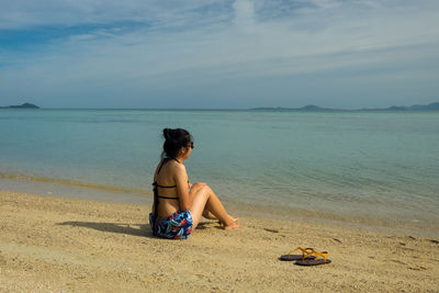 Full length of woman relaxing on shore at beach
