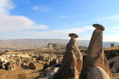 Rear view of woman sitting on rock against sky