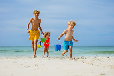 Rear view of shirtless friends standing at beach