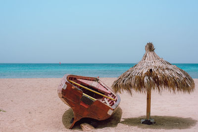 Abandoned lounge chairs on beach against clear sky