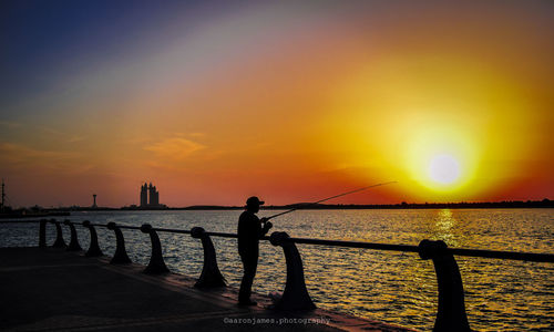 Silhouette people standing on beach during sunset