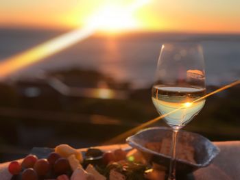 Close-up of beer glass against sunset sky