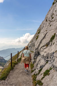 Rear view of woman walking on mountain against sky