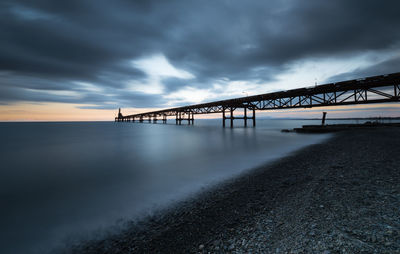 View of bridge over sea against cloudy sky