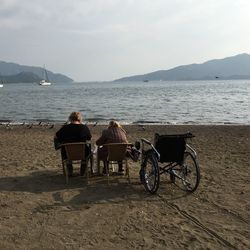 Rear view of women sitting on chairs at beach