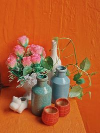 Flower pots on table against orange wall
