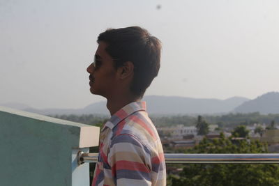 Portrait of young man looking away against sky