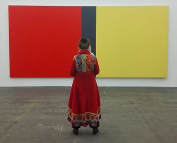 Rear view of woman standing against red wall