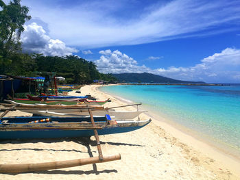 Boats moored on beach against sky