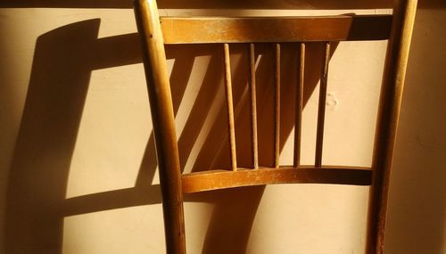 Close-up of wooden chair against wall