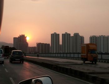 Cars on road in city against clear sky during sunset