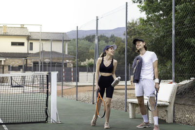 Tennis partners walking on a tennis court with casual soprtswear laughing hardly while having fun 