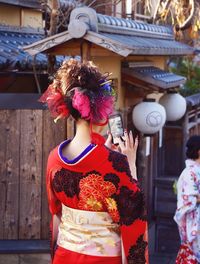 Rear view of woman standing by pink flowers