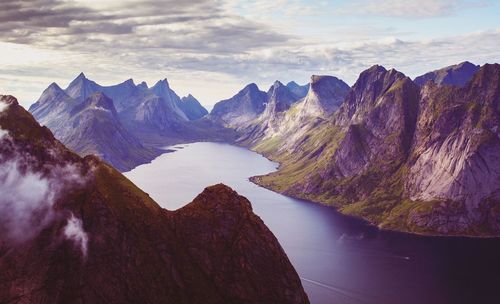 Scenic view of sea amidst mountains against cloudy sky