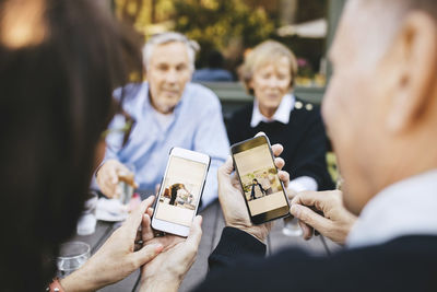 Senior couple looking at photos on mobile phones at outdoor restaurant