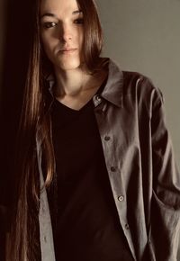 Portrait of young woman standing against gray background