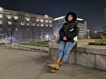 Full length of man sitting in illuminated city at night