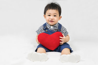 Portrait of cute girl with arms raised sitting on bed at home
