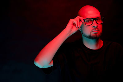 Portrait of man wearing eyeglasses against black background