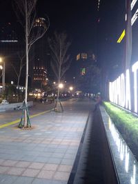 Illuminated street amidst buildings in city at night