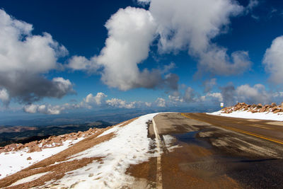 Empty road against cloudy sky during winter