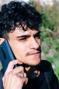 Close up of young man with goatee beard talking on his smartphone.