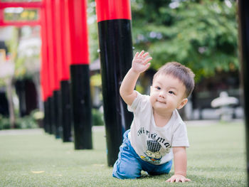 Full length of cute baby boy crawling on field amidst torii gate