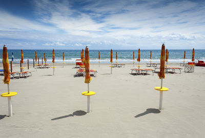 Deck chairs on beach against sky