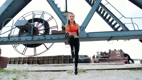 Athletic woman exercising her muscles . at dawn, near a cargo crane, on the sandy quarry beach