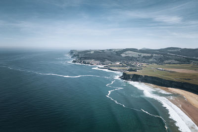 Scenic view of sea along the coastline with cliffs against sky