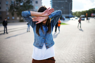 Woman covering face while standing on townsqaure