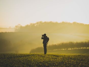 Full length of man standing on field against sky during sunset