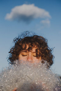 Woman with closed eyes by plastic against blue sky