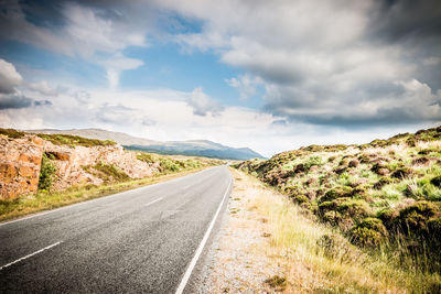 Road leading towards mountain against sky