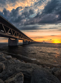 Bridge over sea against sky during sunset