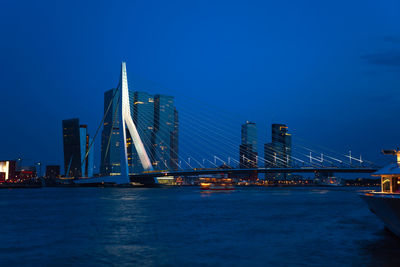 Illuminated bridge over river against blue sky