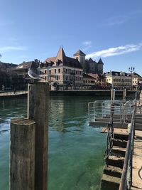 Pier over river by buildings against sky