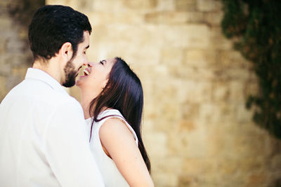 Cheerful couple romancing while standing against wall