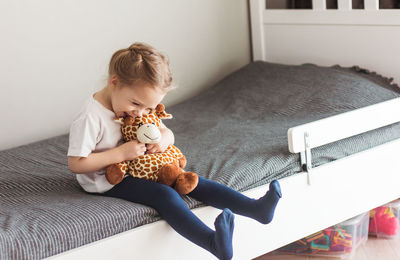 Child  holding a giraffe plush toy on a gray background