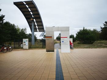 Footpath by street in city against sky