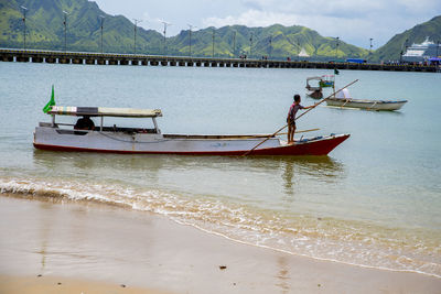 Boat moored on sea shore against mountains